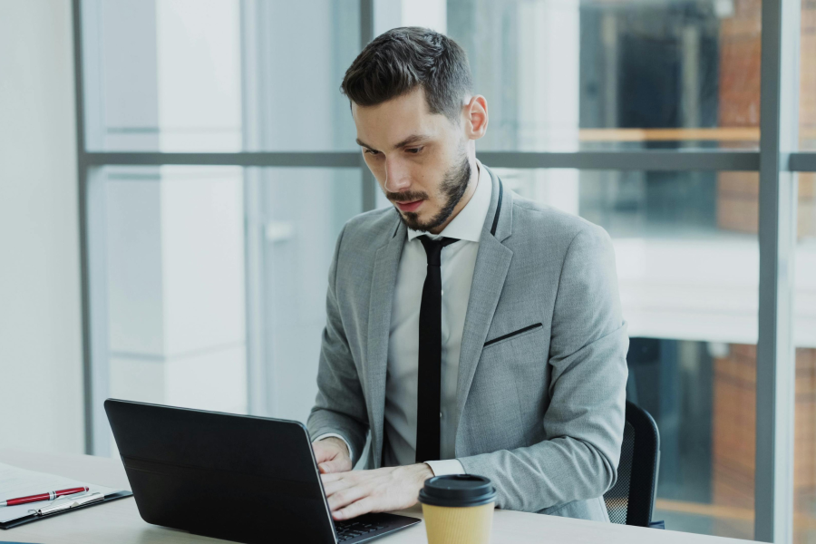 Officer worker, dressed in a suit, typing on a laptop