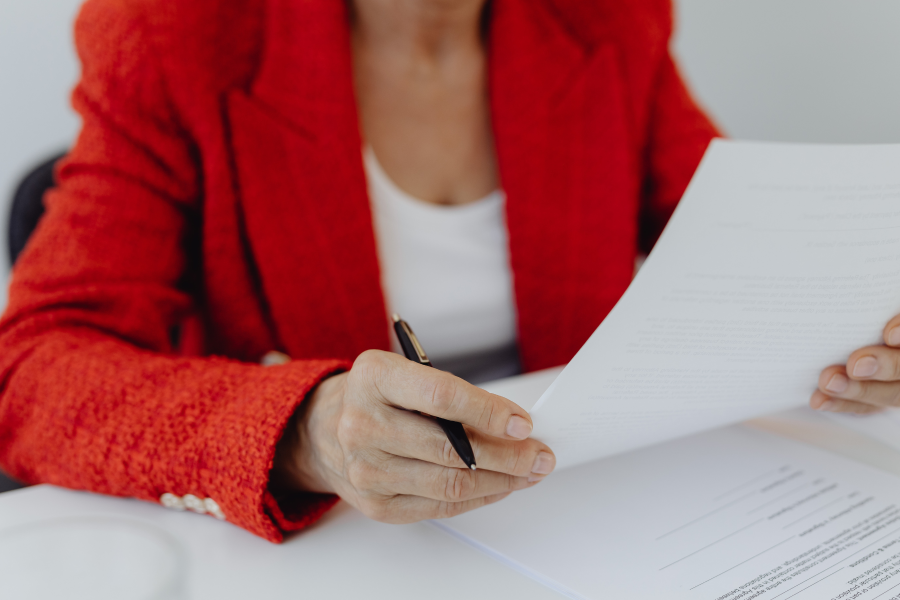 The chest of a person wearing a red blazer, holding a piece of paper