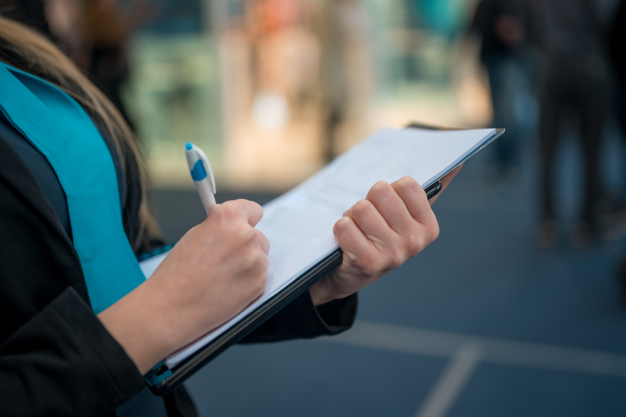 The side profile of a person wearing a blue shirt, writing on a clipboard