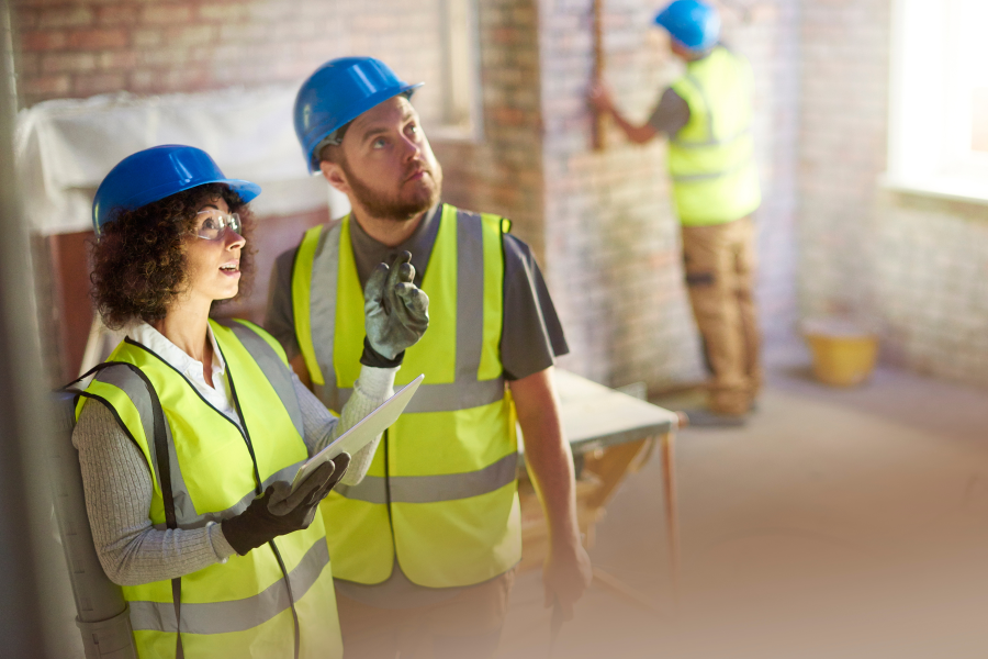 Two construction workers wearing high vis vests and blue hard hats