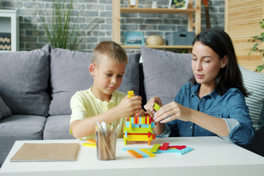 A professional sat building colourful blocks with a young child