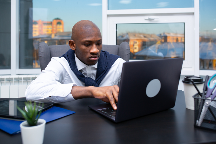 A professional sat at a desk, typing on a laptop