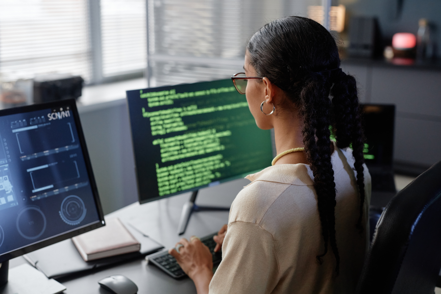 The back of a professional who looks at two computer screens