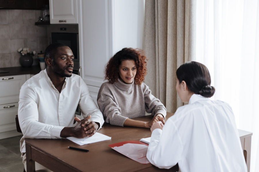 Three individuals sat around a table speaking to one another