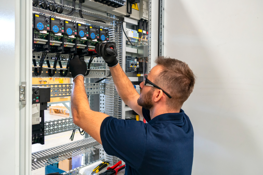 A tradesperson using tools to fix electrical components and wiring