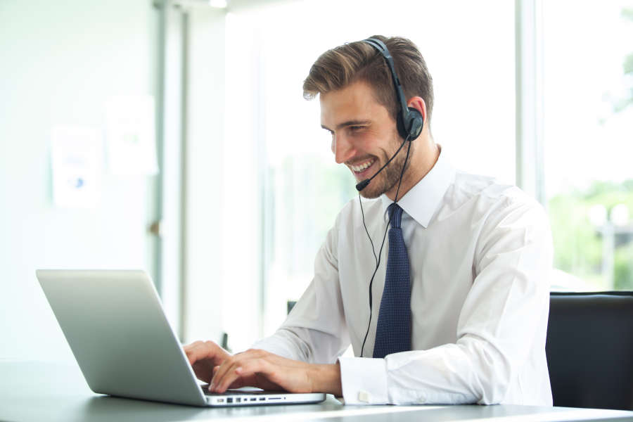 A smart professional using a laptop and speaking into a microphoned headset