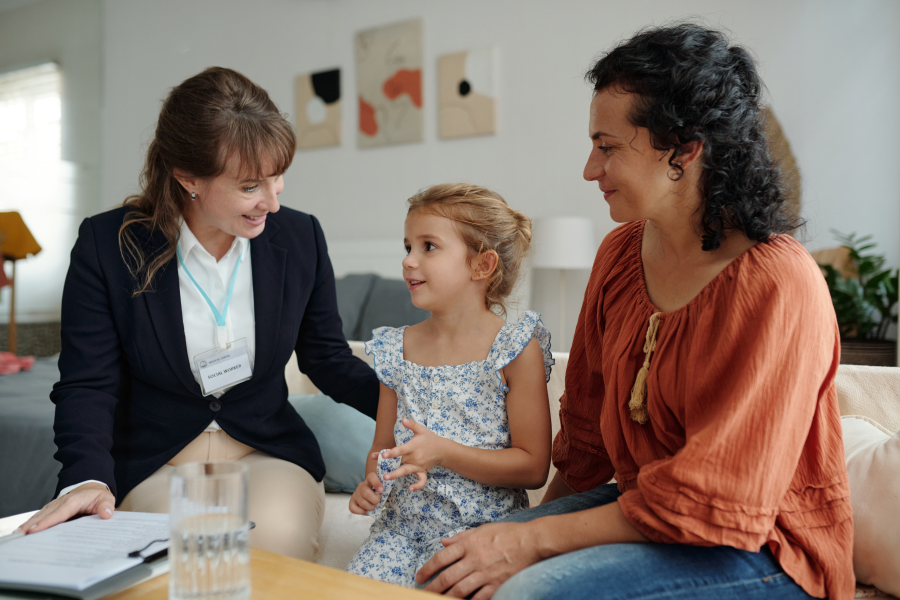 Two individuals sat with a child between them as they speak and smile