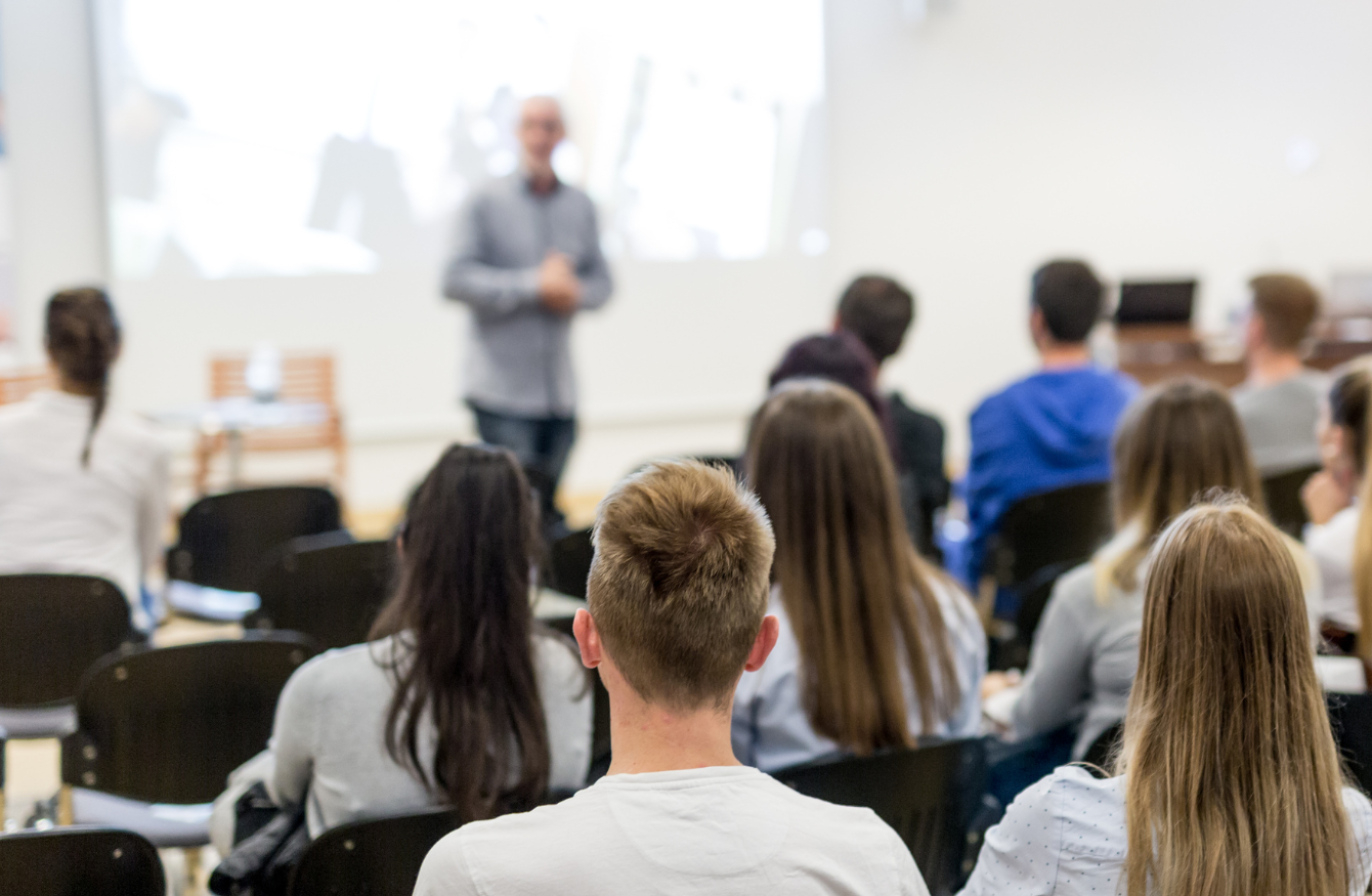 A lecture room full of people listening to a person speaking