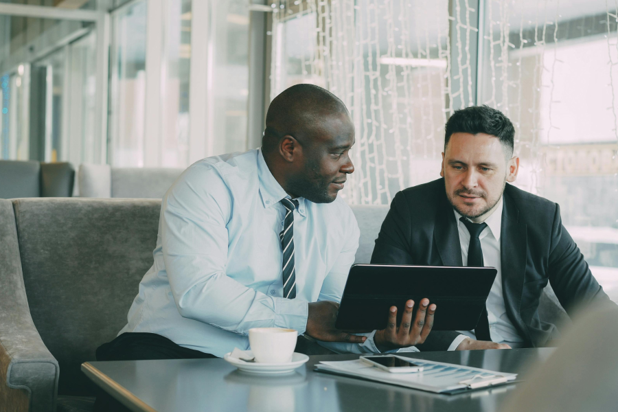 Two professionals sit looking at a digital device screen together