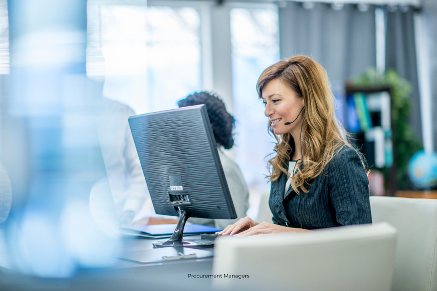 A professional sits in front of a computer wearing a microphone headset