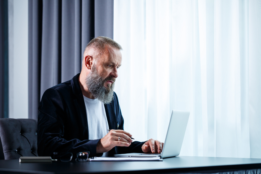 A professional sat in front of a laptop with a pen in their hand