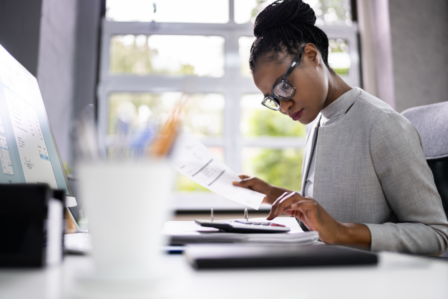 A professional holding a piece of paper and typing into a calculator