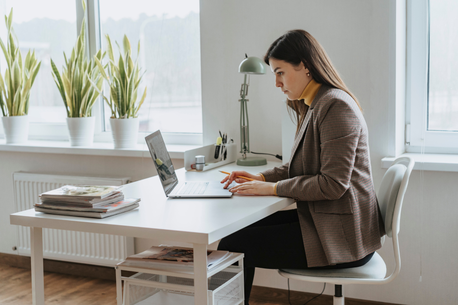 A professional sitting at a desk resting their hands on an open laptop