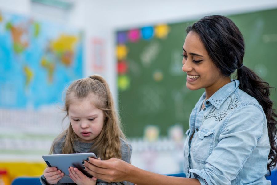 Tutor overlooking a young child on an electronic device