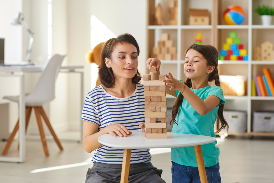 A professional and young child playing Jenga together