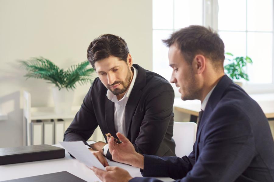 Two adults looking at a piece of paper and talking