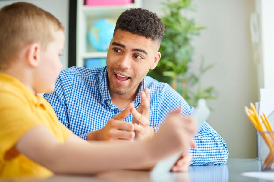 Tutor speaking to a young child who is holding an electronic device