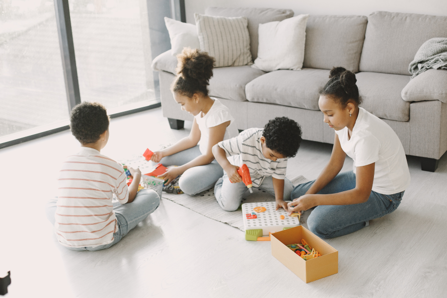 Four children sitting on the floor playing with toys