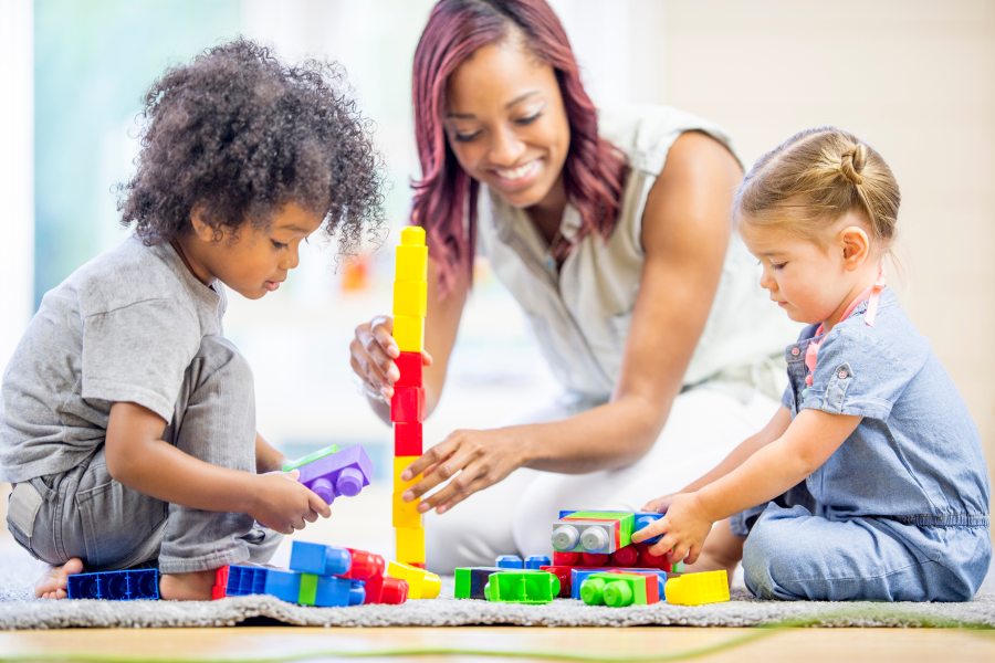 Two children and an adult building a tower with colourful blocks