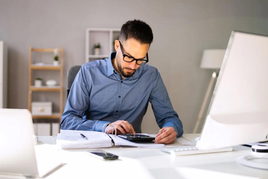 A professional using a calculator at a desk
