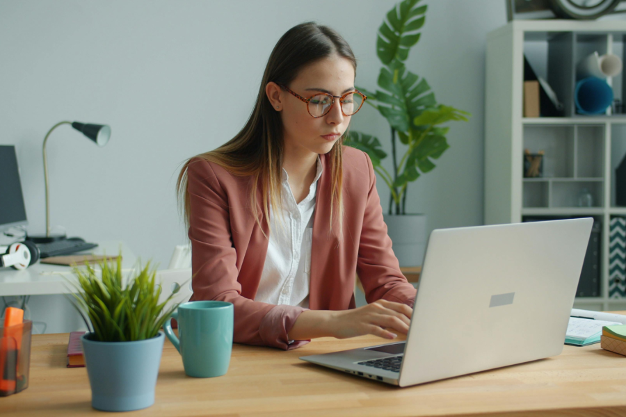 An adult sat at a desk looking at a laptop