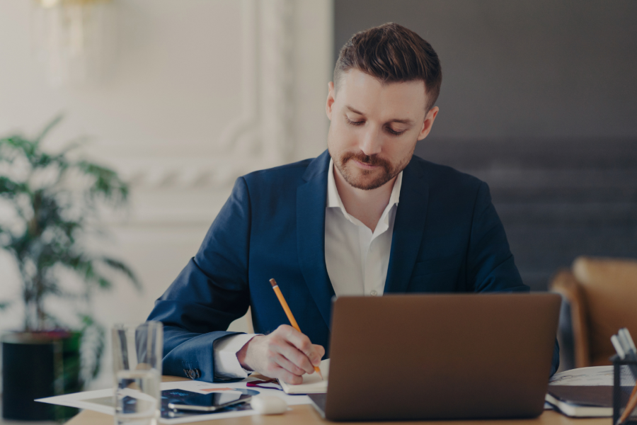 An adult sat at a desk writing on a piece of paper