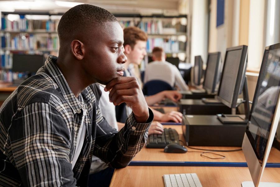 Teenage student looking at a computer screen in a library