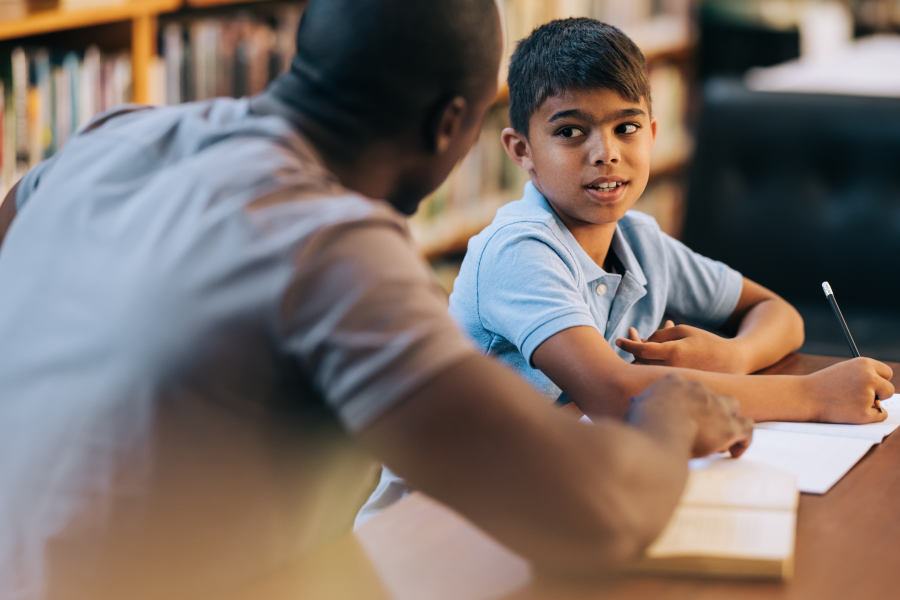 An adult and young child sitting together to complete school work