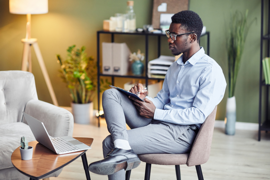 A professional sitting on a chair with a pen and paper in their hand