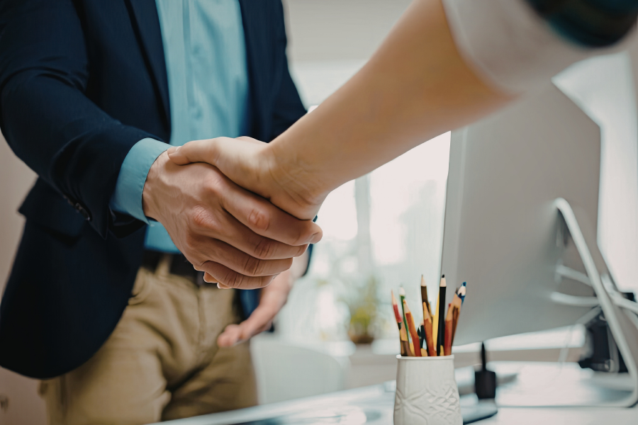 Two hands shaking each other across a desk