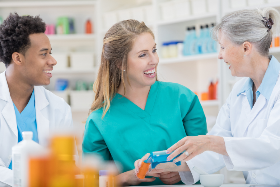 Three healthcare professionals smiling at each other