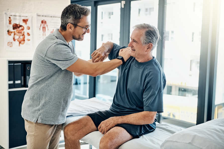 A healthcare professional helping an elderly gentleman with an arm exercise