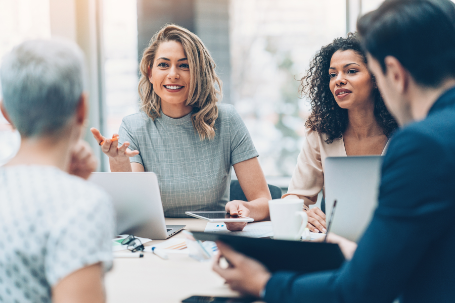 Four professionals sat around a table speaking and smiling