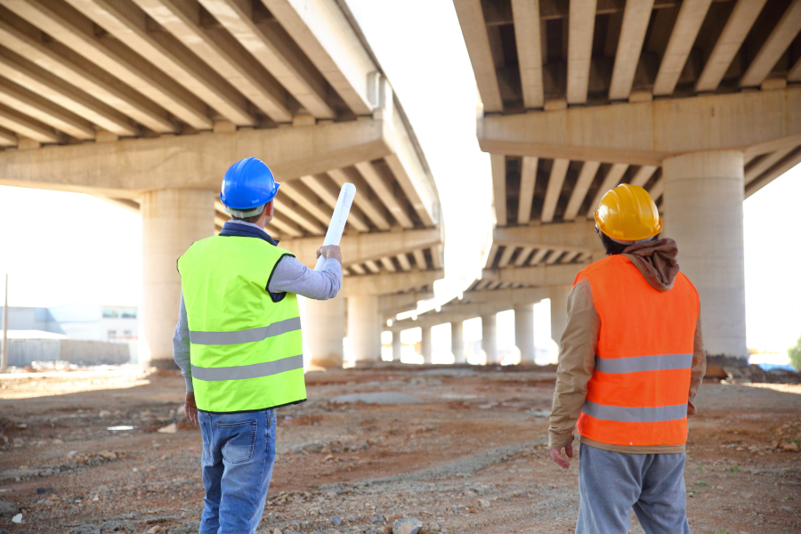 The back of two construction workers looking at a bridge structure