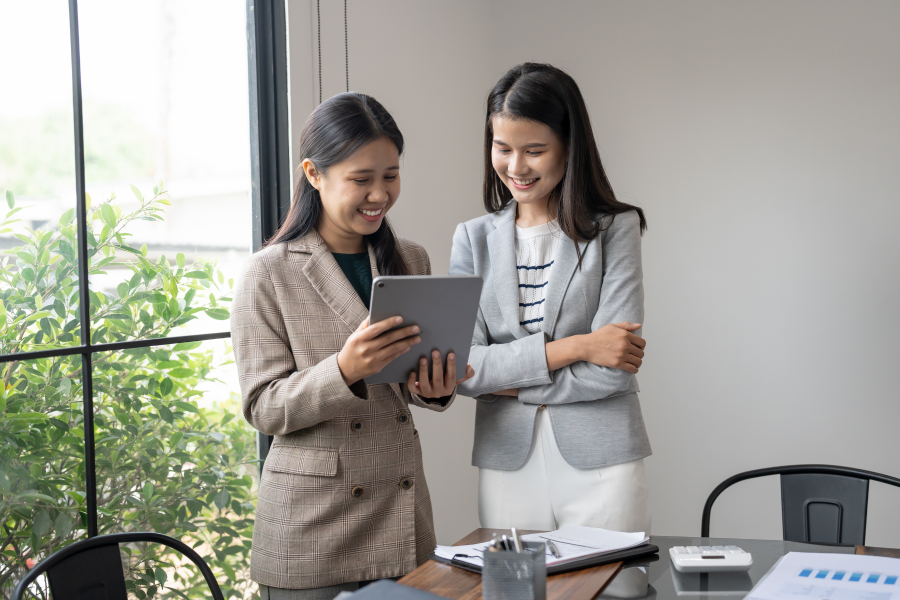 Two professionals smiling and looking at a digital device