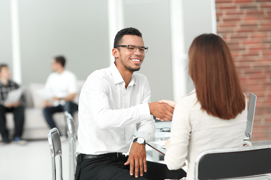 Two professionals wearing white shirts, smiling and shaking hands
