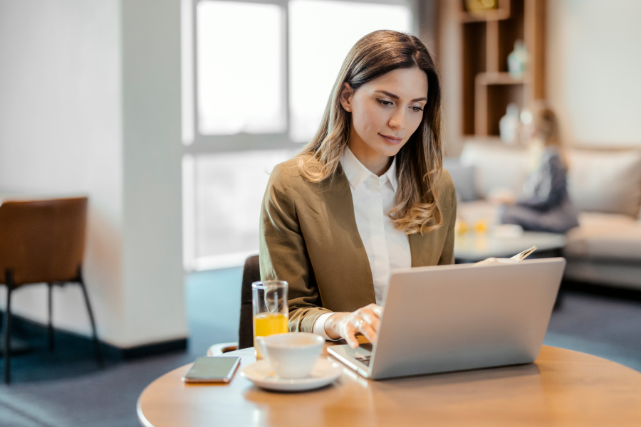 A professional wearing a brown blazer, looking at a laptop screen
