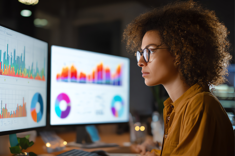 A professional wearing glasses sat in front of two computer screens