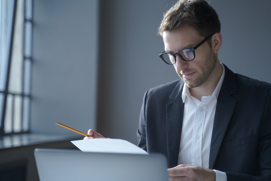 A professional wearing a suit and glasses sat looking at a piece of paper
