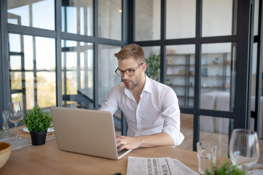 A professional wearing glasses and a white shirt sat looking at their laptop