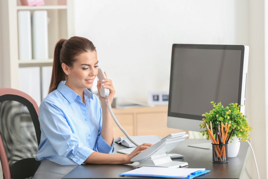 A professional wearing a blue shirt, sitting at a desk whilst speaking on the telephone