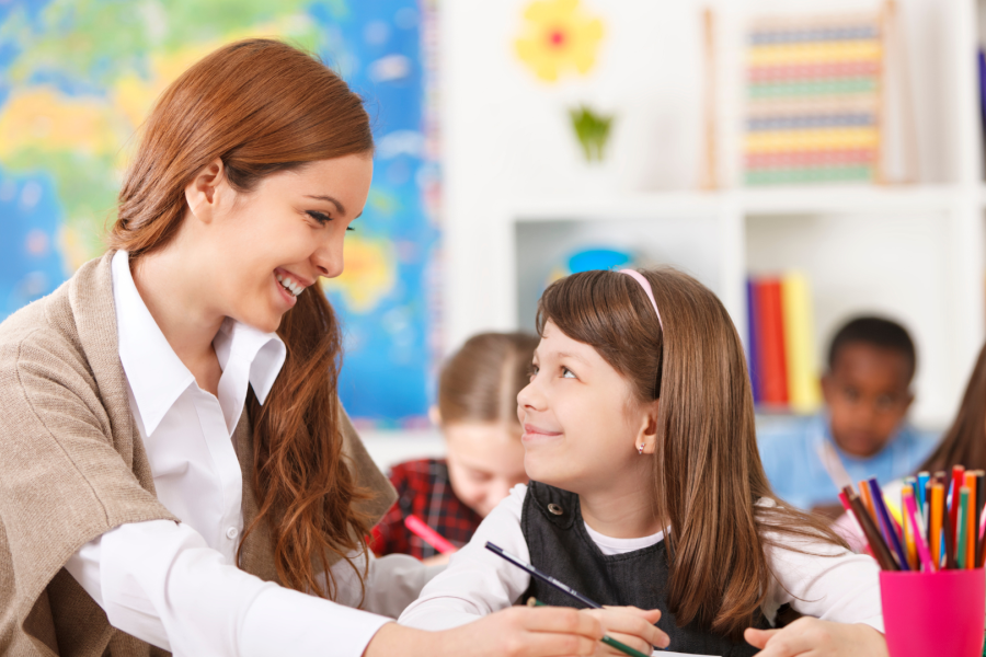 An adult sat with a young child in a classroom