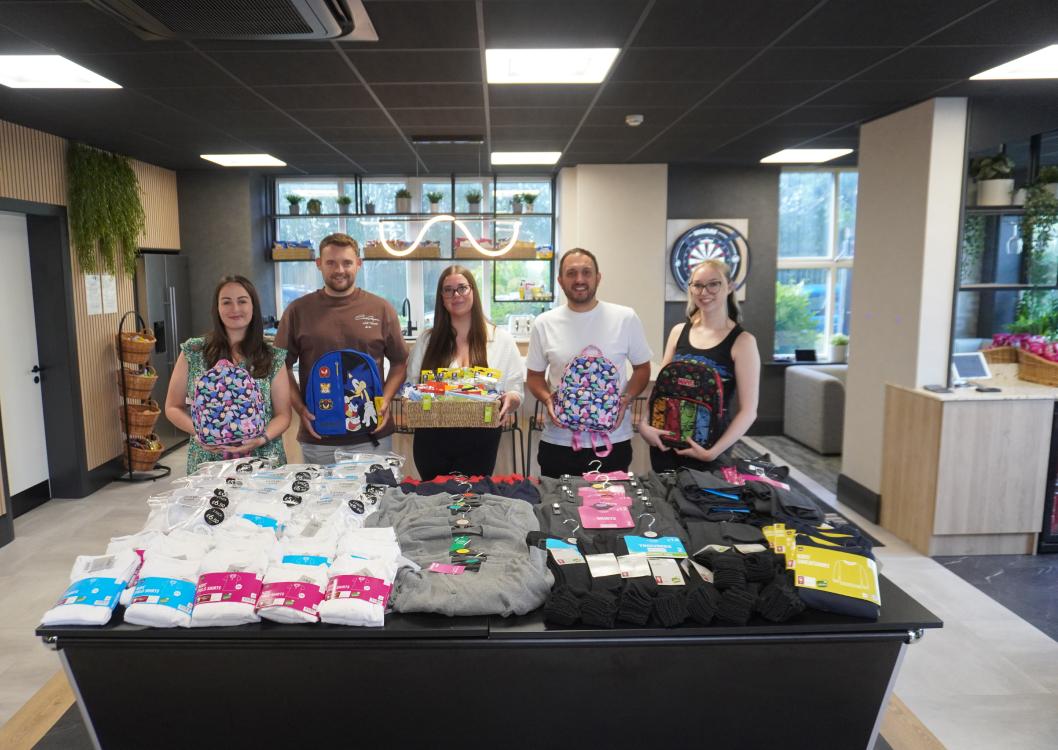 Spencer Clarke Group employees stood around a table of school uniform donations