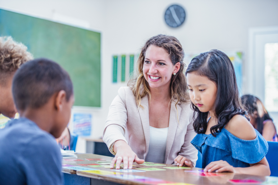 A professional sitting with young students, helping them with a school task