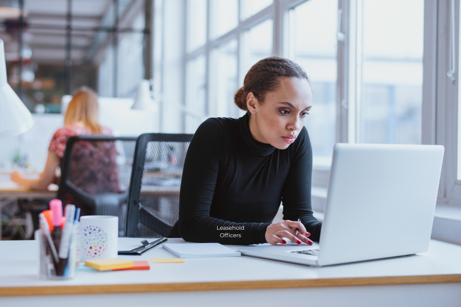 A professional wearing a black jumper, looking at their laptop screen