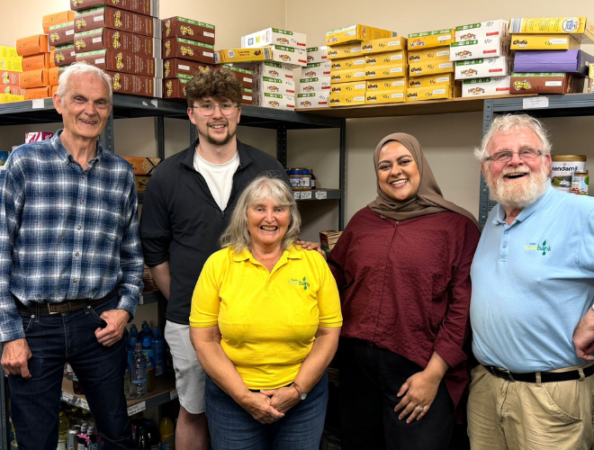 Two Spencer Clarke Group employees and three volunteers at a foodbank