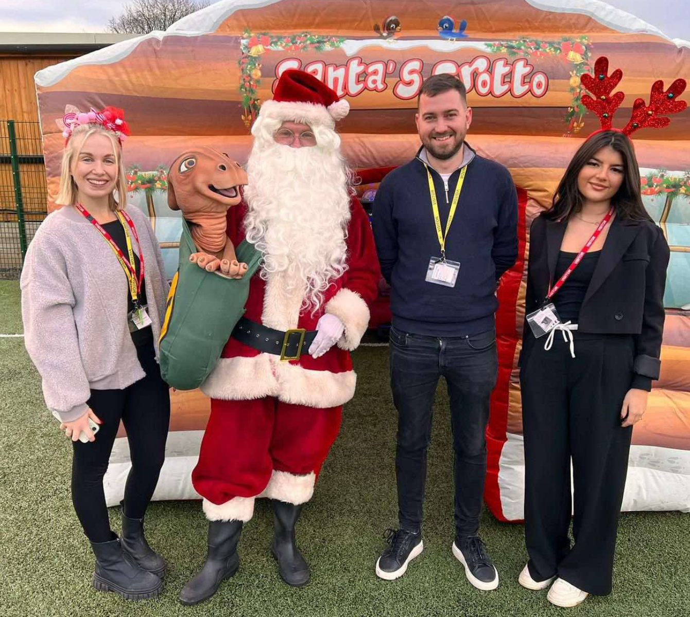 Three Spencer Clarke Group employees stood outside a Christmas grotto with Father Christmas