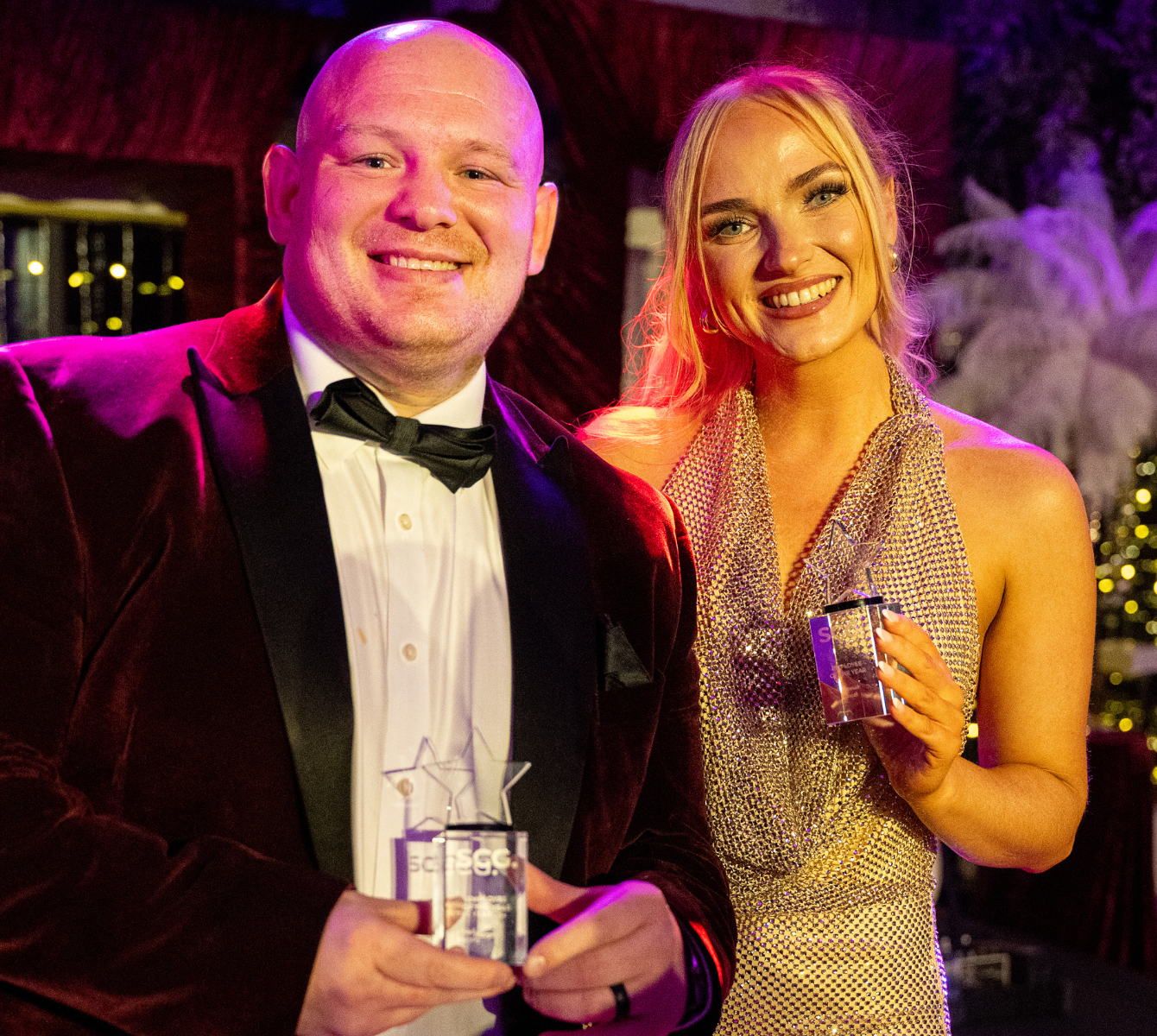 Two Spencer Clarke Group employees smiling and holding awards