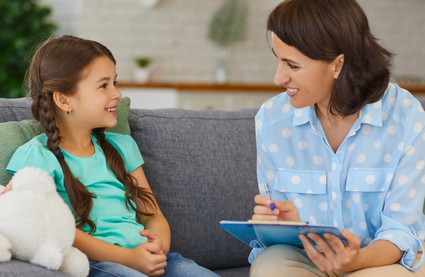 A professional wearing a blue shirt with white spots, speaking to a young child
