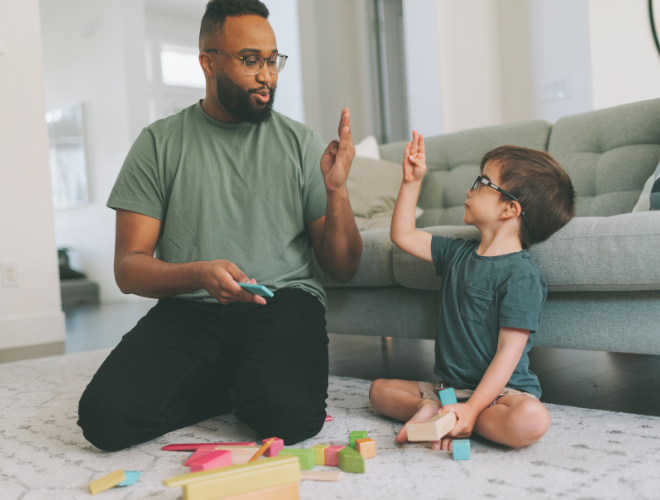 An adult sitting on the floor with a young child, playing with colourful blocks